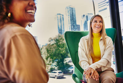 employee value proposition una donna sorridente in primo piano che parla con un'altra donna inquadrata di spalle